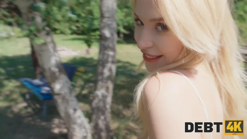 Millie glances back over her shoulder with a teasing look between the birch trees